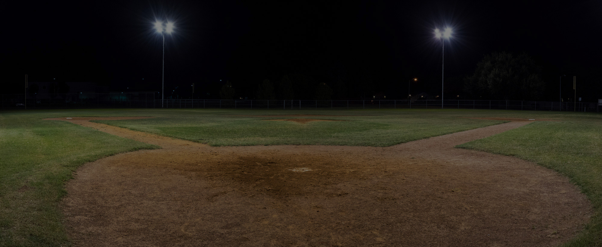 Panorama of empty baseball field at night from behind home plate